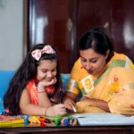 Homemaker guiding child at home, preparing for preschool teacher training and online NTT course.