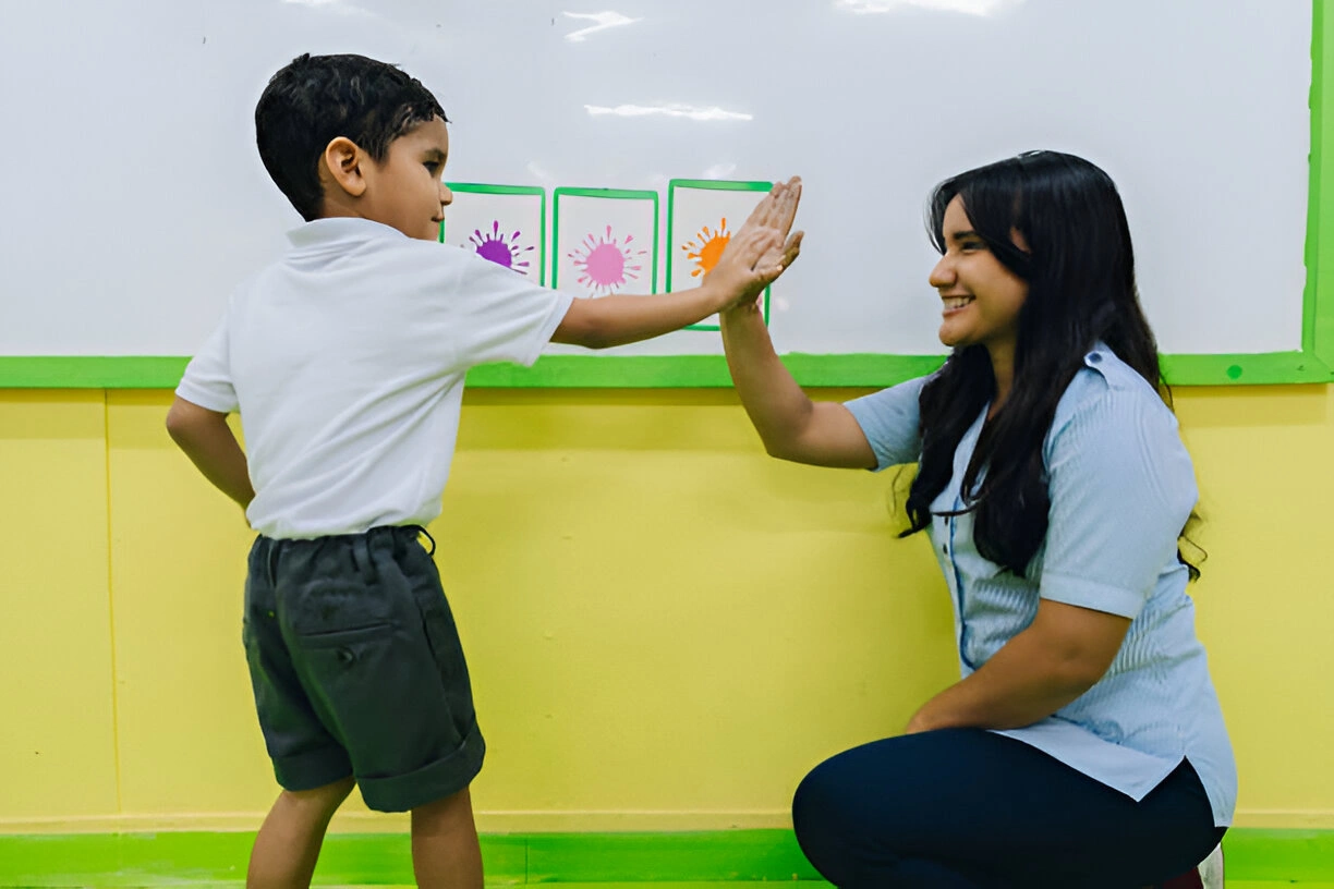 Preschool teacher training with child during classroom activity.