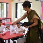 Teacher supporting students in classroom, relevant to diploma in special education online and remedial education course.