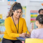 Teacher helping a child with a classroom activity during a diploma in special education course.