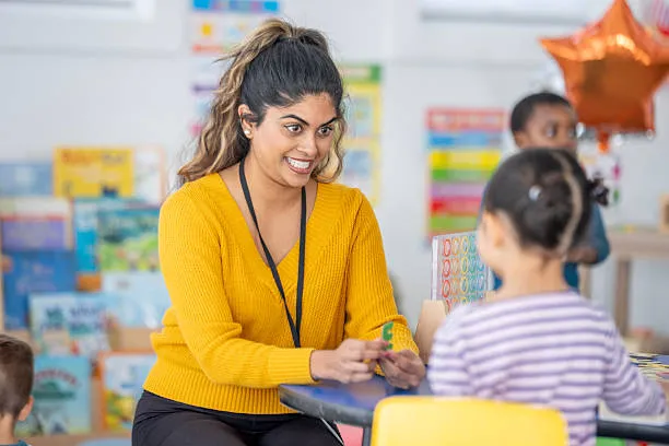 Teacher helping a child with a classroom activity during a diploma in special education course.